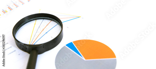 Graph and chart on a white background with a magnifying glass.