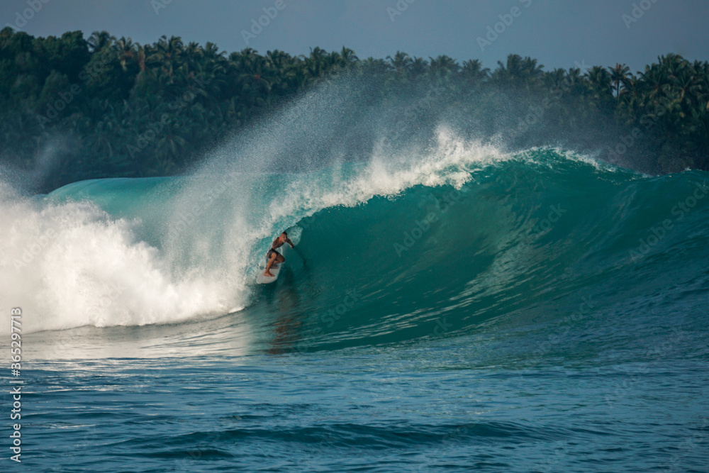 Surfer on perfect blue big tube wave, empty line up, perfect for surfing, clean water, Indian Ocean in Mentawai islands.