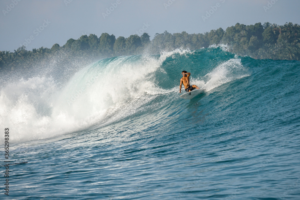 Surfer on perfect blue big tube wave, empty line up, perfect for surfing, clean water, Indian Ocean in Mentawai islands Surfer on perfect blue big tube wave, empty line up, perfect for surfing, clean water, Indian Ocean in Mentawai islands