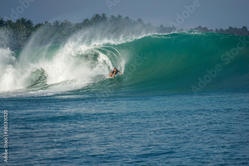 Surfer on perfect blue big tube wave, empty line up, perfect for surfing, clean water, Indian Ocean in Mentawai islands