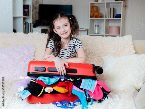 Happy girl with suitcase and belongings at home