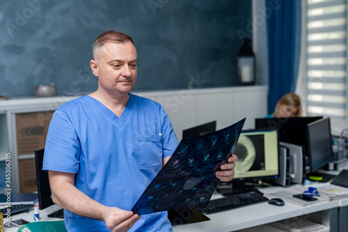 Doctor holding a picture of a brain MRI workflow in diagnostic hospital. Healthcare, roentgen, people and medicine concept. © Vadim