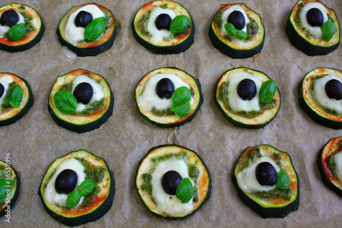 Baked zucchini rings with pesto, mozzarella, olives, and basil