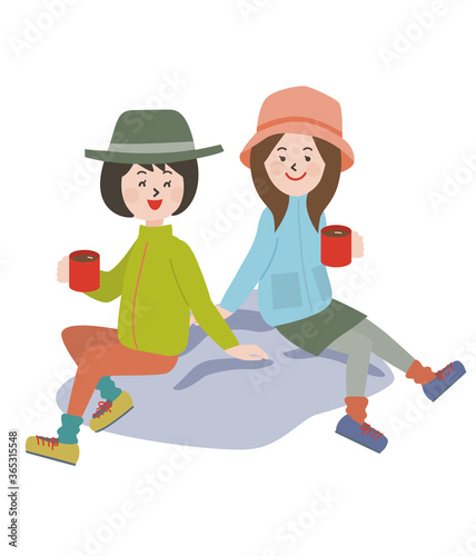 岩に座りコーヒーを飲むアウトドアスタイルの若い2人の女性