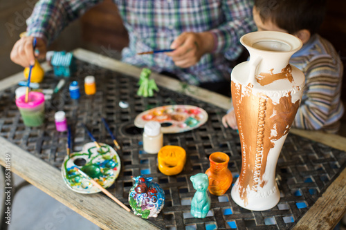 Father and son paint a vase