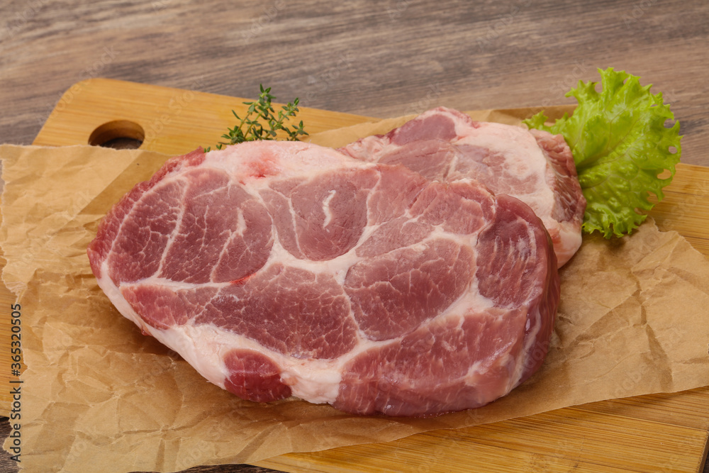 Raw pork steak over wooden board