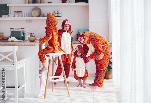 cheerful kids with mother in kigurumi pajamas having fun in the morning on the kitchen photo