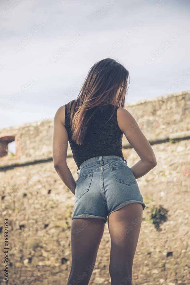 Sexy woman in fashion blue jeans shorts. Perfect hot booty and erotic  curves hips concrete background. Beautiful seductive woman in jeans shorts.  Back view. Stock Photo | Adobe Stock