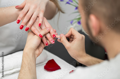 Manicure. Closeup Of Beautiful Woman Hands Polishing Nails With Red Nail Polish In Beauty Salon. Close-up Of Beautician Hand Painting Female Client Nails. Beauty Concept. High Resolution