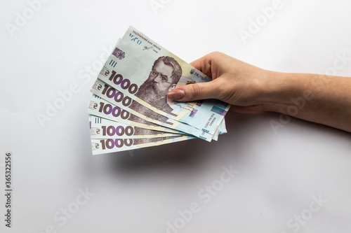 Female hands holds a five thousand hryvnia. Ukrainian currency with woman's hands against a white background. Five thousand hryvnia with one thousand hryvnia five bills. Ukrainian money. Banknotes