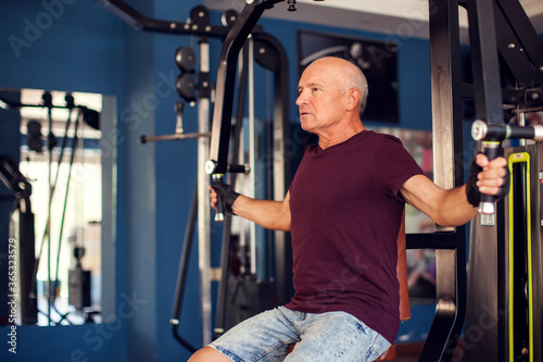 A portrait of senior man in the gym training chest muscles. People, health and lifestyle concept