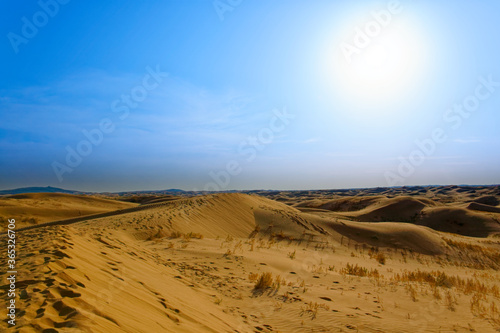 Sand dunes in the Gobi Desert in Inner Mongolia, China. sandy desert with blue sky and apparent sun, few clouds, extraordinary travel scene, hostile and inhospitable places to live