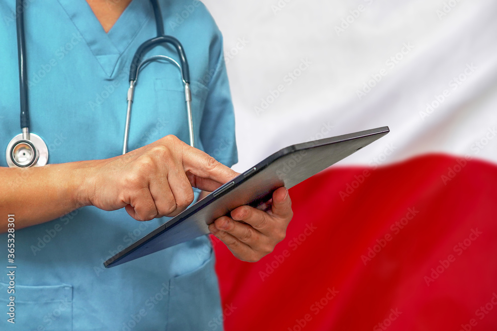 Surgeon or doctor using a digital tablet on the background of the Poland flag. Surgeon or doctor using a digital tablet on the background of the Poland flag.
