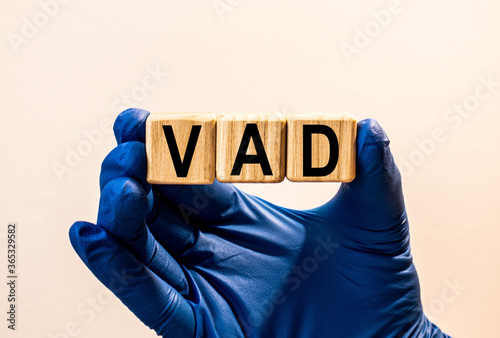 The word VAD which is made from wooden cubes. Hands in a blue glove. Isolated on WHITE background. photo