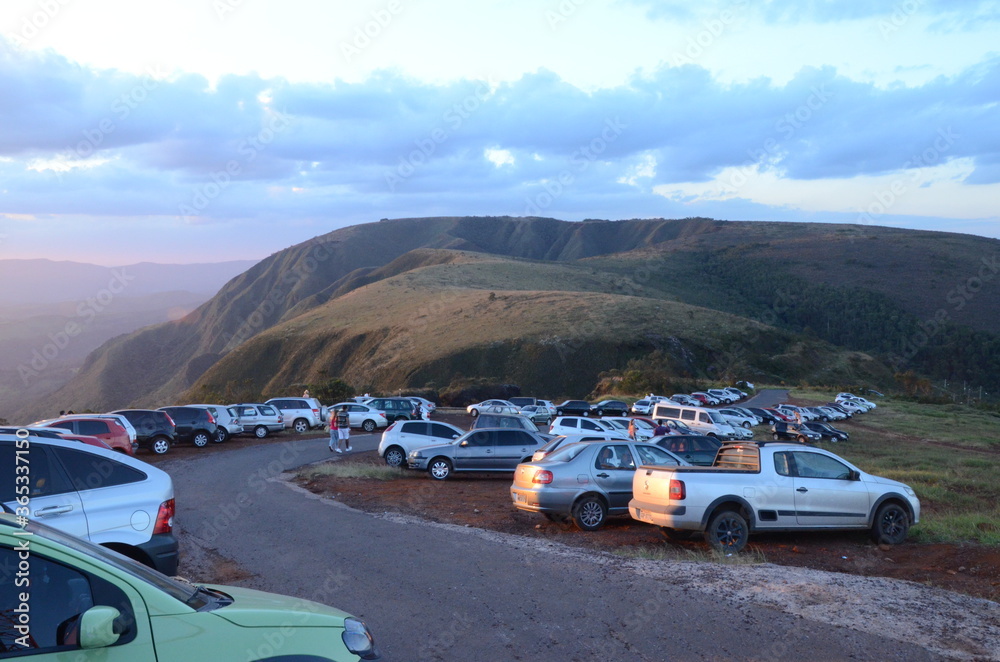 Cars lined up at sunset on a curve in Topo do Mundo (translated to Top of the World) in Minas Gerais