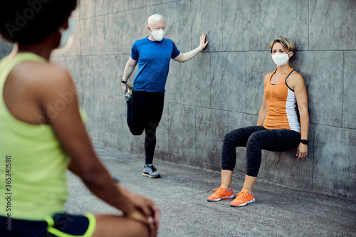 Small group of athletes wearing face masks while warming up outdoors.