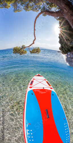 Fototapeta Naklejka Na Ścianę i Meble -  Colorful paddle board against azure sea in Brela, Croatia