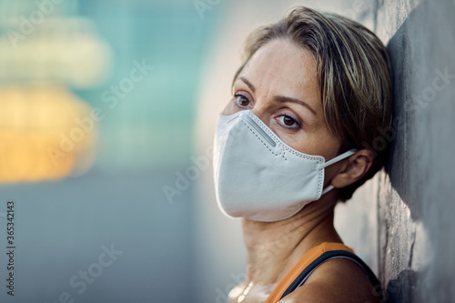 Pensive athletic woman with protective face mask outdoors.
