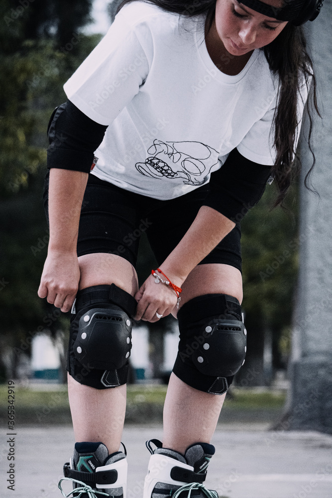 Fototapeta premium Joven mujer ajusta sus rodilleras antes de patinar