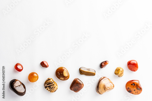 Brown semi-precious stones arranged neatly with a empty space above them on a white background