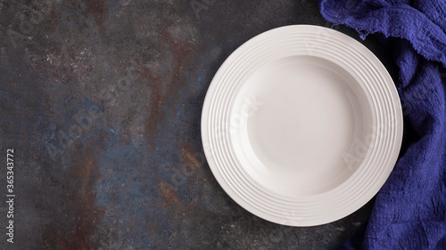 Top view of empty white plate on a dark background. Copy space