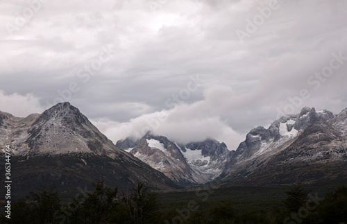 Alpine landscape. View of the forest and mountain range with rocky peaks  under a dramatic cloudy sky. 