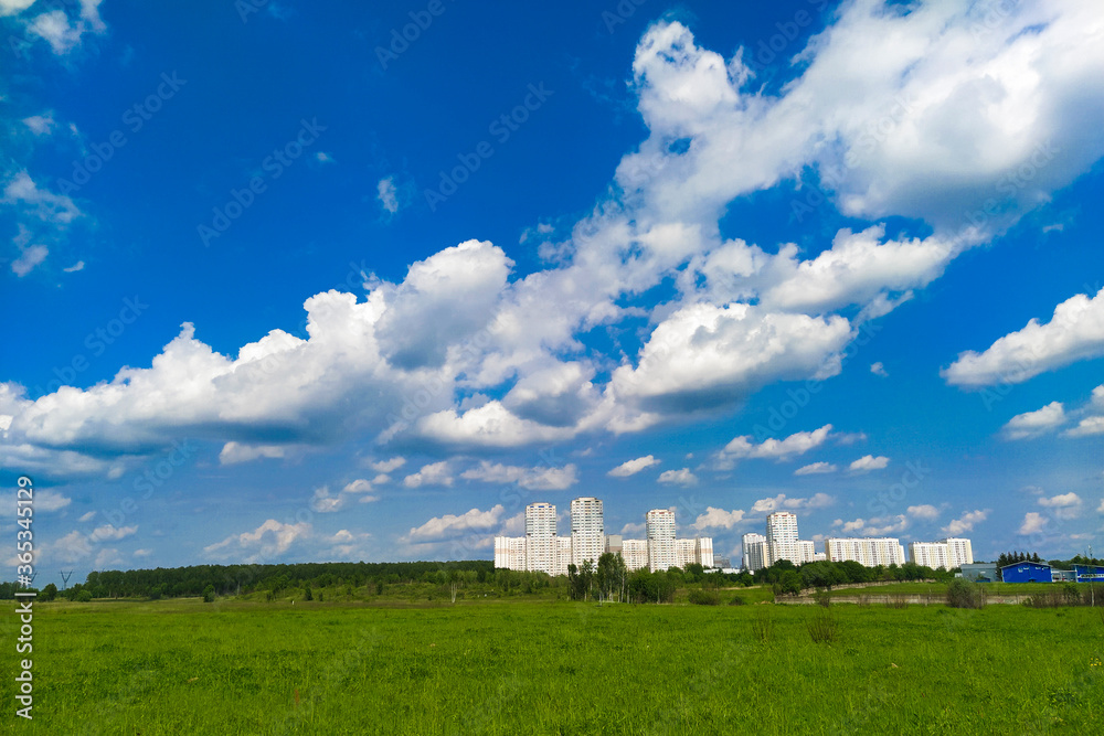 landscape with a summer field and a city visible in the distance