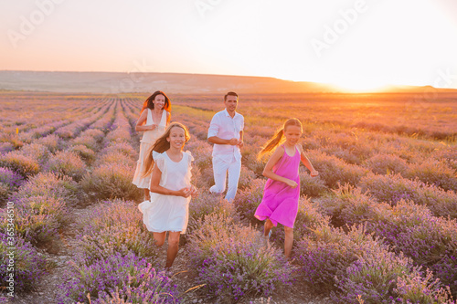 Family in lavender flowers field at sunset in white dress and hat