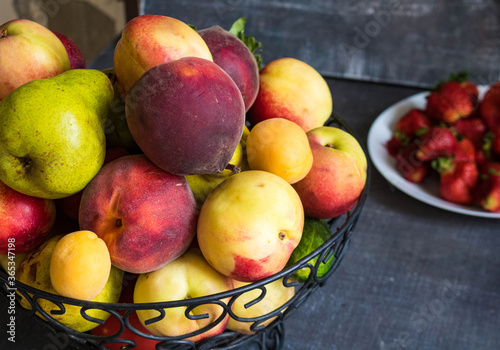 On the table is a fruit bowl. In a vase peaches  plums  nectarines and pears. Life style.