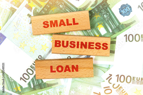 Against the background of euro bills, the text is written on wooden blocks - small business loan