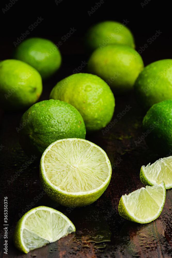 Fresh, raw and organic sliced green lemon in focus with other lemons in composition Fresh, raw and organic sliced green lemon in focus with other lemons in composition