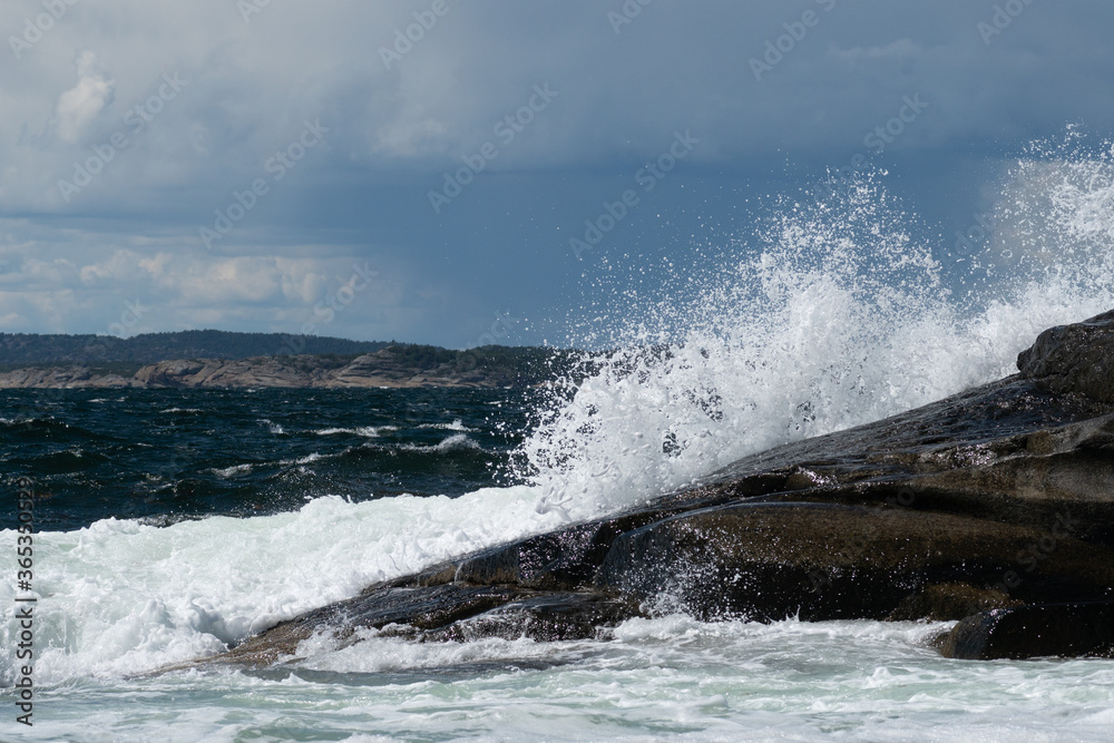 Huge waves crashing in over the norwegian shorline, leaving a salty mist in the air