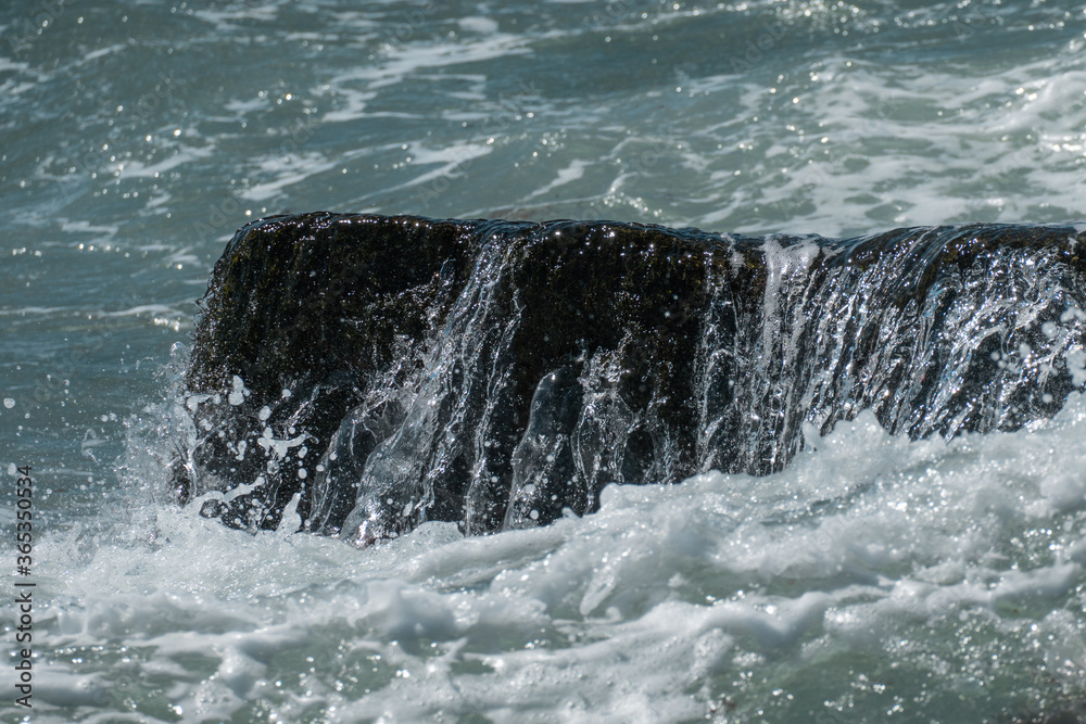 Fototapeta premium Water splashing over a rock in the atlantic ocean, creating a beautiful image