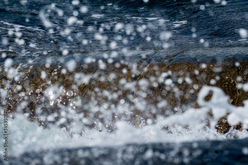 A wave crashing into the rocks off the norwegian shore, leaving beautifully arranged droplets hanging in the air