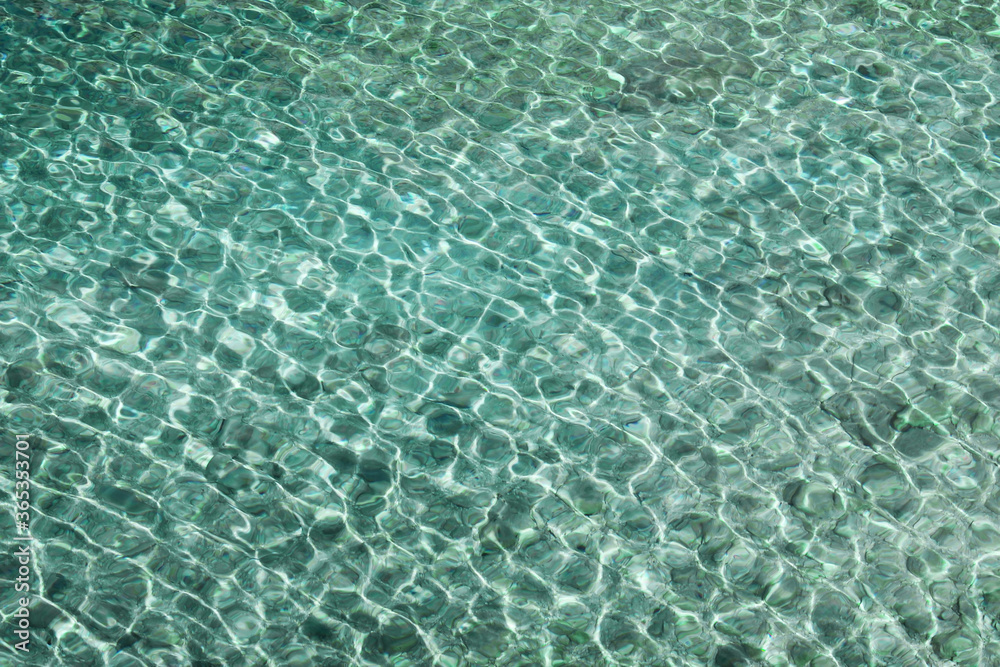 Abstract blue sea water with sunlight reflections, shallow depth, natural background concept.
