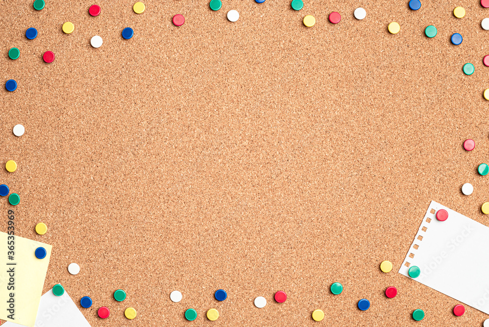 Flat lay of blank papers on a cork board with multi colored thumb tacks making a frame around the board Flat lay of blank papers on a cork board with multi colored thumb tacks making a frame around the board