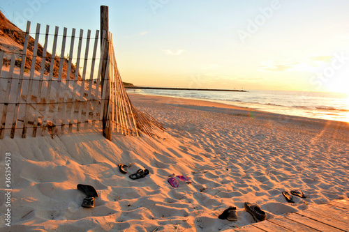 Summertime on Cape Cod, Massachusetts. Long shadows and warm late afternoon sunlight illuminate this typical Cape Cod beach scene with abandoned footwear left by beachgoers. photo
