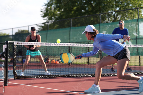 A woman hits a dink shot while playing pickleball. photo