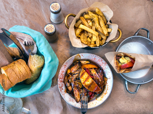 Top view with greek traditional dishes, lahanika - vegetables with cheese, pita with souvlaki, bread and fried potatoes with oregan. photo