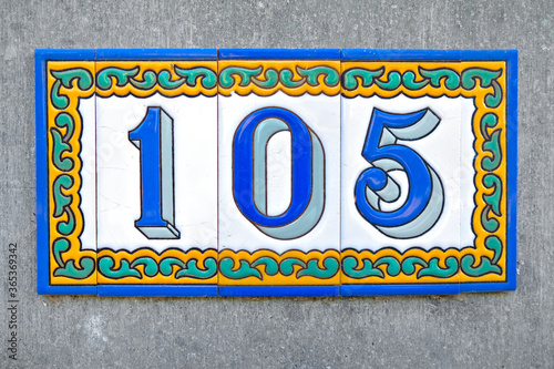 Number 105, one hundred and five, in blue digits on gary background. photo