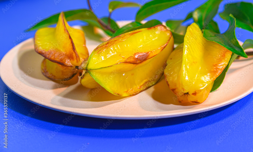 carambola fruits served on plate on blue background
