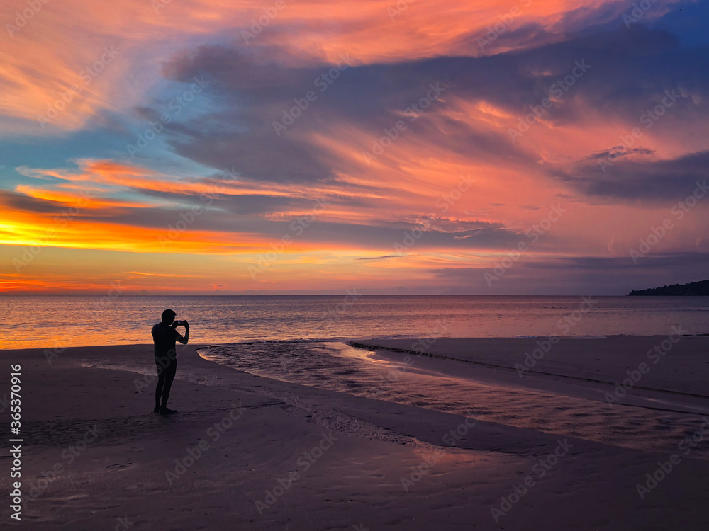 Panoramic view of sunset a man taking photo at Karon beach in Phuket, Thailand