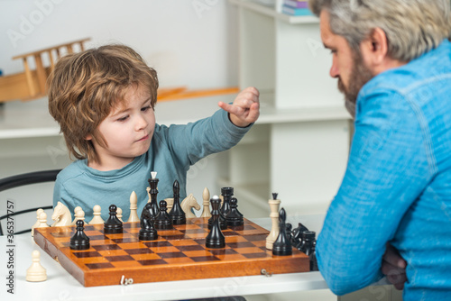 Father with son playing Chess at home. Back to school. Father teaching his son to play chess.