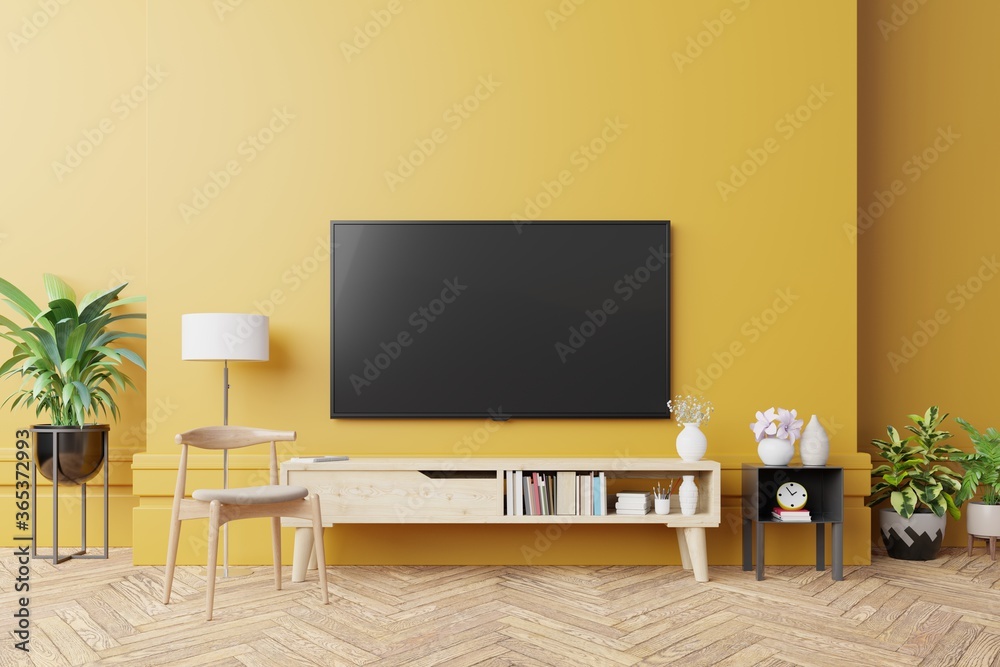 TV on cabinet in modern living room with lamp,table,flower and plant on yellow wall background. - obrazy, fototapety, plakaty 