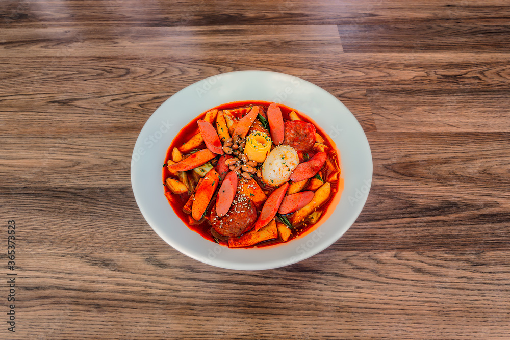 Korean Budae Tteokbokki at a 45 degree angle on a wood table in a white bowl.