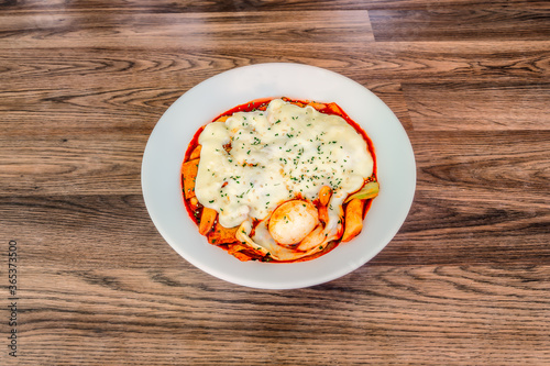 Obraz na płótnie Korean Cheese Tteokbokki at a 45 degree angle on a wood table in a white bowl. w salonie
