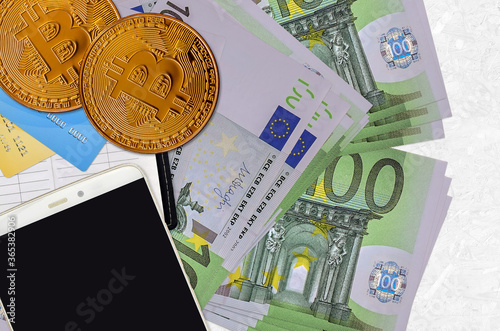 100 Euro bills and golden bitcoins with smartphone and credit cards. Cryptocurrency investment concept. Crypto mining or trading photo