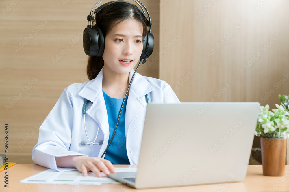 Young attractive Asian female doctor diagnosis talking and looking to camera in video conference ,Positive doctor waving and having online consultation on digital tablet laptop Young attractive Asian female doctor diagnosis talking and looking to camera in video conference ,Positive doctor waving and having online consultation on digital tablet laptop