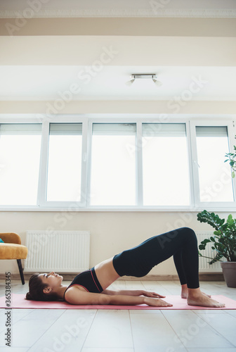 Caucasian woman in activewear doing fitness at home on floor in a light room