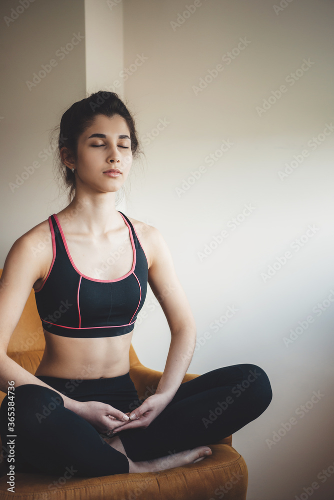 Front view photo of a caucasian lady wearing sportswear meditating on armchair with closed eyes
